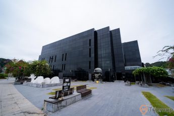 Bảo tàng Quảng Ninh, nhà kính màu đen, tượng người thợ mỏ, ghế đá, cây xanh, ảnh chụp ban ngày