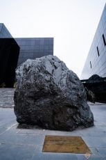 Bảo tàng Quảng Ninh, nền đường màu xám, tảng đá to màu đen, nhà kính màu đen, bậc thang màu xám, ảnh chụp ban ngày