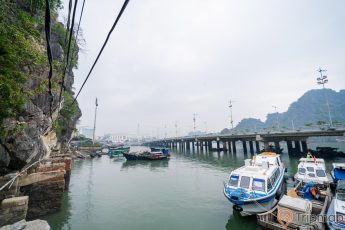 Cầu Bài Thơ, nhiều thuyền đang đỗ trên mặt nước, nước biển màu xanh, ngọn núi đá màu xám có cây xanh, nhiều ngọn núi phía xa, ảnh chụp ban ngày