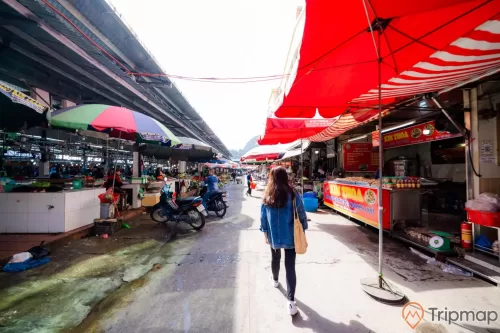 Chợ Hạ Long, Chợ Hòn Gai, cô gái mặc áo xanh đang đi trên nền đường màu xám, nhiều ô màu đỏ, nhiều xe máy, trời nắng, ảnh chụp ban ngày