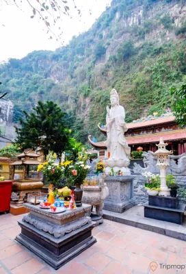 Chùa Long Tiên, tượng Phật Quan Thế Âm Bồ Tát, Lư Hương, nền gạch màu đỏ, nhiều cây xanh, ngọn núi đá nhiều cây xanh phía sau, ảnh chụp ban ngày