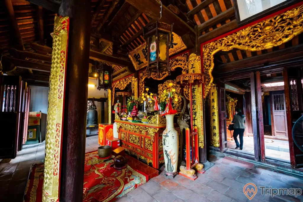 Đền thờ Đức Ông Trần Quốc Nghiễn, nền gạch màu đỏ, cây cột nhà màu nâu, gian thờ màu vàng, trần nhà bằng gỗ màu nâu