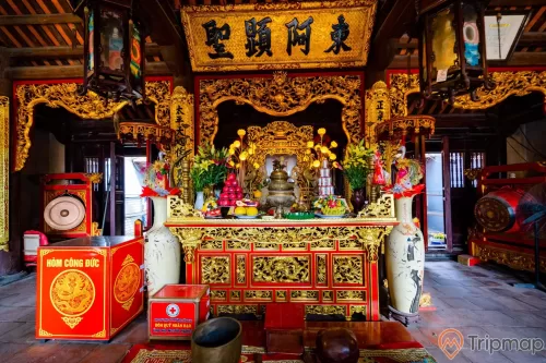 Đền thờ Đức Ông Trần Quốc Nghiễn, gian thờ màu có hoa văn màu vàng, hòm công đức, 2 cái bình màu trắng, nền gạch màu đỏ, trần nhà bằng gỗ màu nâu