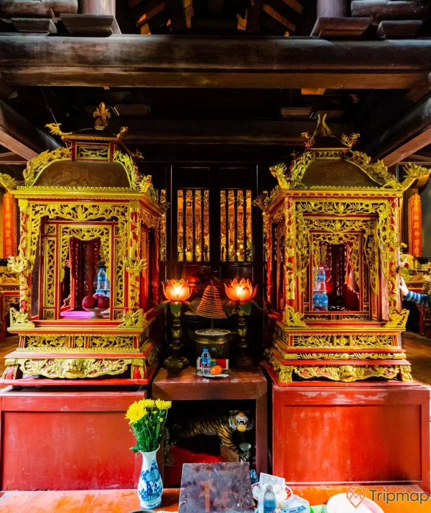Đền thờ Đức Ông Trần Quốc Nghiễn, 2 gian thờ có hoa văn màu vàng, lọ hoa, trần nhà bằng gỗ màu nâu, đèn hình hoa sen