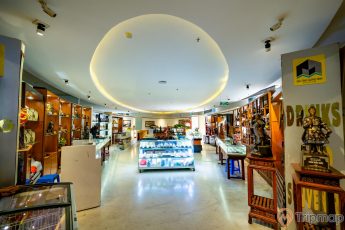 Bảo tàng Quảng Ninh, nền gạch bằng đá màu nâu nhạt, trần nhà màu trắng, nhiều tượng bằng đồng, nhiều tủ gỗ