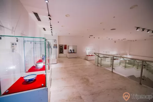 Bảo tàng Quảng Ninh, nơi lưu giữ những giá trị lịch sử, nhiều tủ kính trưng bày hiện vật, nhiều bát đặt trên tấm vải đỏ, nền nhà bằng gạch có hoa văn, trần nhà màu trắng