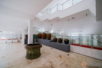 Bảo tàng Quảng Ninh, nơi lưu giữ những giá trị lịch sử, nhiều bình màu nâu được đặt trên bệ màu xám, cột nhà màu trắng, trần nhà màu trắng, nền nhà bằng gạch có hoa văn, nhiều tủ kính