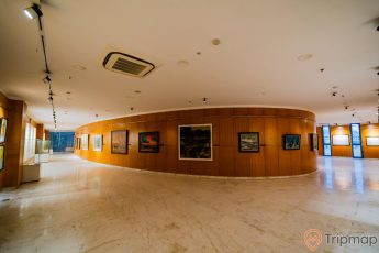 Bảo tàng Quảng Ninh, nơi lưu giữ giá trị lịch sử, hành lang dài, nhiều bức tranh treo trên bức tường bằng gỗ màu nâu, nền nhà bằng gạch có hoa văn, trần nhà màu trắng