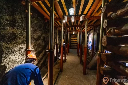 Khu tái hiện lịch sử hình thành mỏ than, bảo tàng Quảng Ninh, mô hình người công nhân mặc áo xanh, nhiều thanh gỗ to, nền đất màu nâu