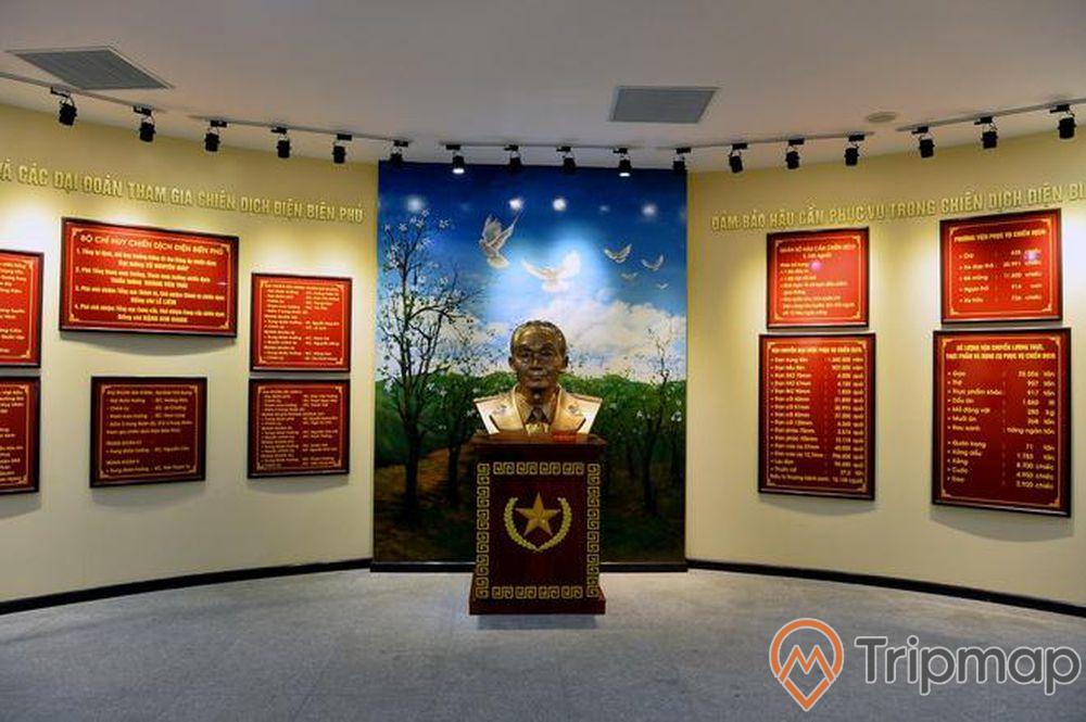 Bảo tàng chiến thắng Điện Biên Phủ, bức tượng đại tướng Võ Nguyên Giáp, bức tượng ở giữa, nhiều bảng nội quy màu đỏ và bức tranh treo trên tường, ảnh chụp trong nhà