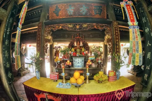 bàn thờ bên trong chùa Hạ tại tây phương, bàn thờ có đĩa hoa quả và 2 bình hoa loa ly, 1 đĩa bánh chocco-pie, 2 cây nến và 1 lư hương bằng sứ, ảnh chụp bên trong chùa
