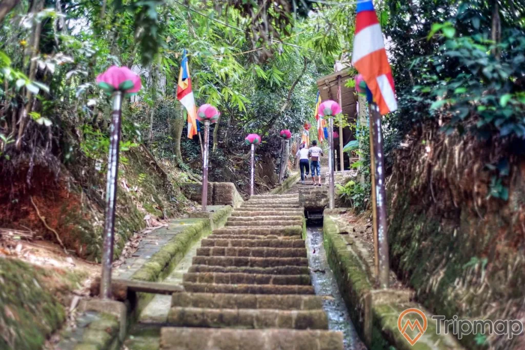 Lối đi lên chùa tây phương, từ Tam quan hạ có 237 bậc thang lát đá ong, cột đèn đường 2 bên đường bậc thang, cây cối mọc 2 bên vách núi, 2 người đang đi lên chùa,