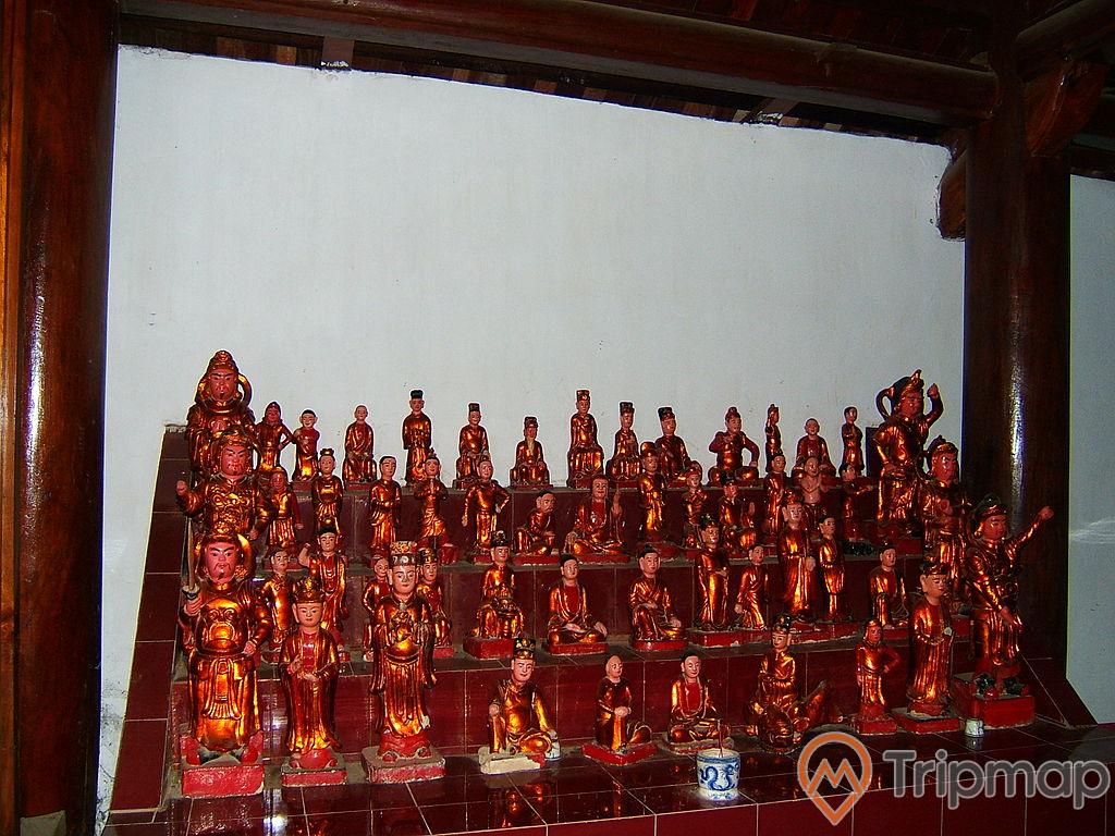 bàn thờ trong chùa Trăm Gian, nhiều bức tượng phật trên bàn thờ, lư hương bằng sứ đặt trên bàn thờ, ảnh chụp trong nhà