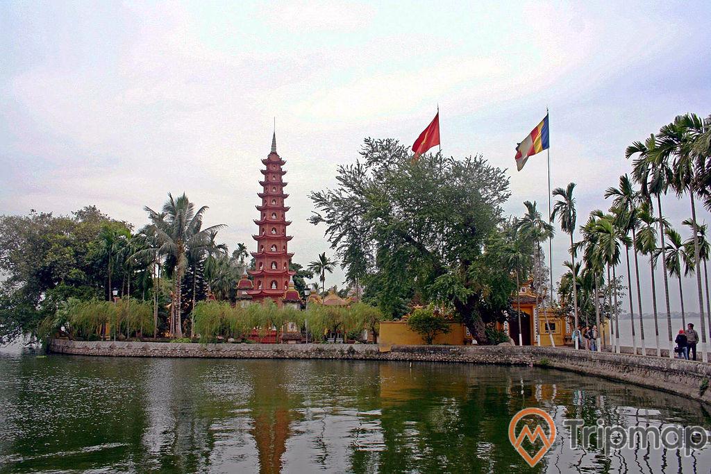 tháp chùa Trấn Quốc màu đỏ, 2 lá cờ bay phất phới, cay cối ở xung quanh chùa xanh tươi bên bờ hồ nước
