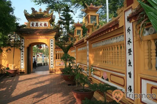 lối đi vào cổng chùa lát gạch đỏ, chậu cây cảnh và cây cối ở cạnh bờ tường lối đi vào chùa Trấn Quốc