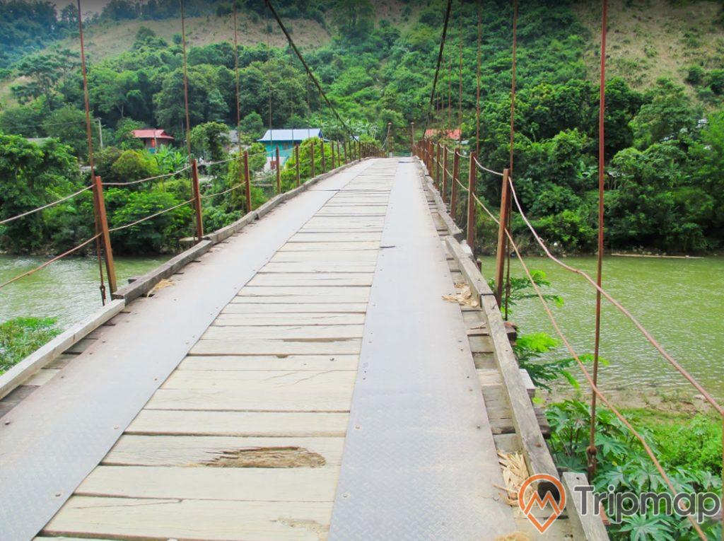 cây cầu đi tới địa điểm du lịch hang động pa thơm, cây cầu treo bằng gỗ bắc qua dòng sông, cây cối xanh tươi, ảnh chụp ngoài trời