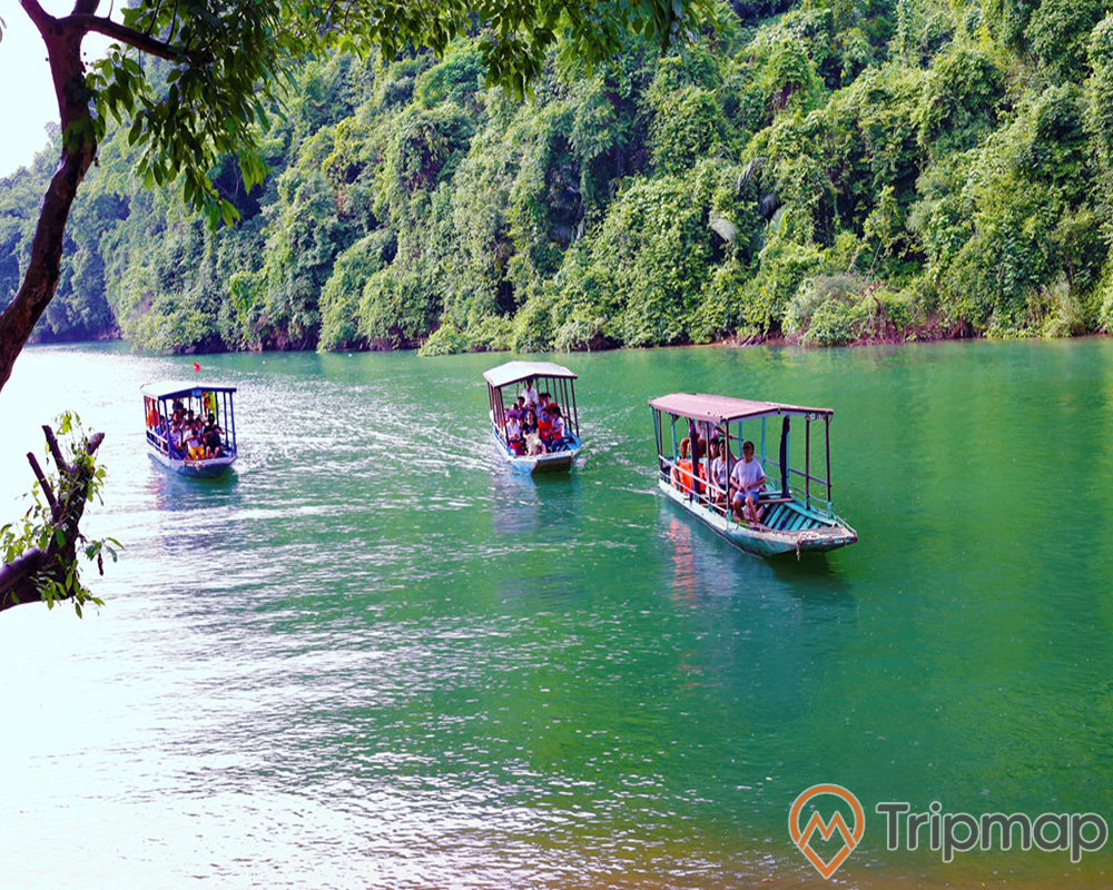 du khách tham quan hồ ba bể, nhiều người ngồi trên 3 chiếc thuyền đang đi giữa hồ nước, cây cối xanh tươi ven hồ và vách núi