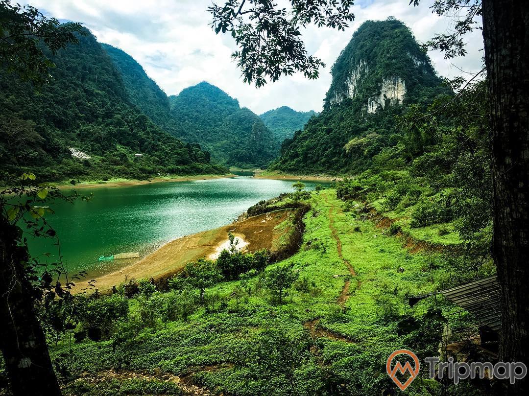 Thiên nhiên thơ mộng tại Hồ Thang Hen, đồi núi cây cối ở phía xa, cỏ ven hồ nước bầu trời nhiều mây, ảnh chụp từ trên cao