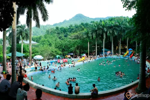 bể bơi ngoài trời khu du lịch Ao Vua, mọi người đang tắm trong bể bơi, cây cối ở ven bể bơi và trên dồi núi đồi phía xa
