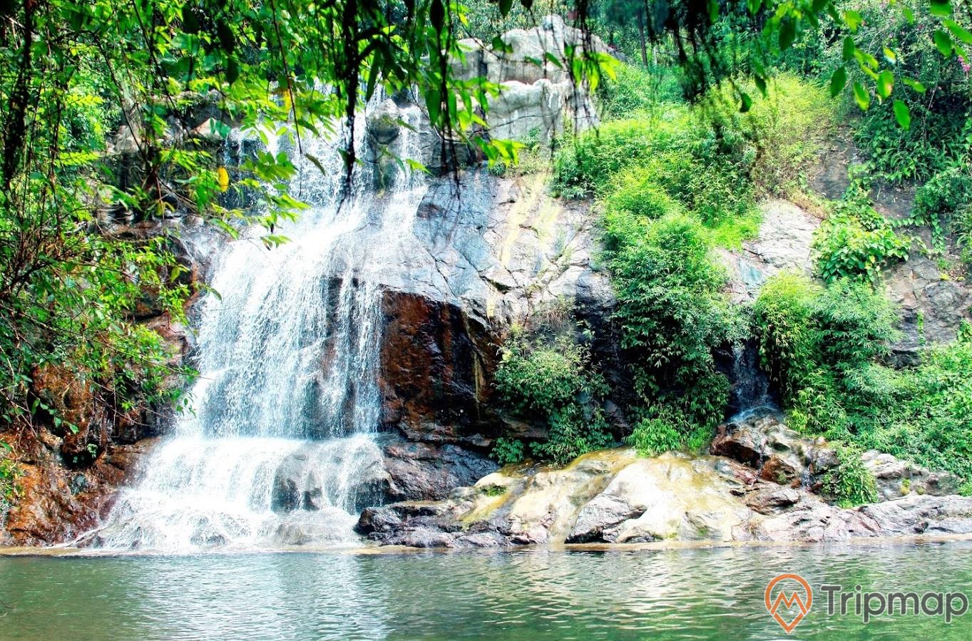 Thác ở khu du lịch Ao Vua, thác nước đang chảy xuống hồ nước, cây cối mọc trên vách núi đá, 