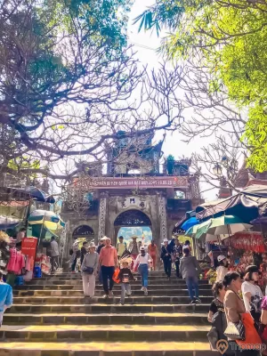 ảnh chụp mọi đường đang đi xuống và đi lên chùa, ô màu sắc của hàng quán phía hai bên bậc thang đi bộ lên chùa Hương, cây cối trơ trụi lá và tán lá tre xanh, cổng chùa Hương