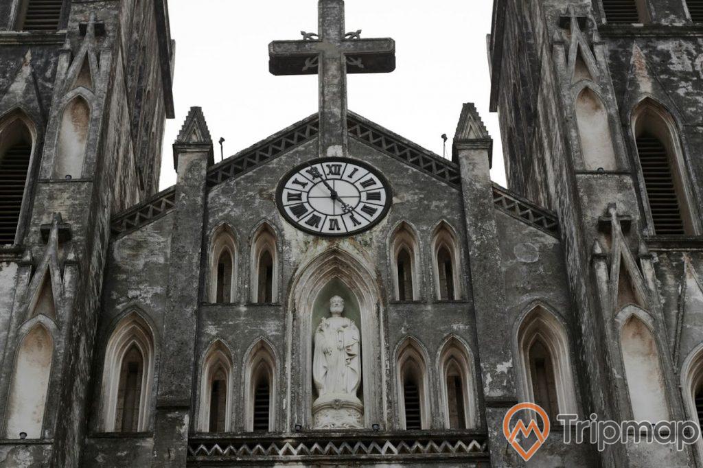 đỉnh nhà thờ lớn Hà Nội có cây thánh giá và 1 bức tượng thánh giuse và 1 chiếc đồng hồ,