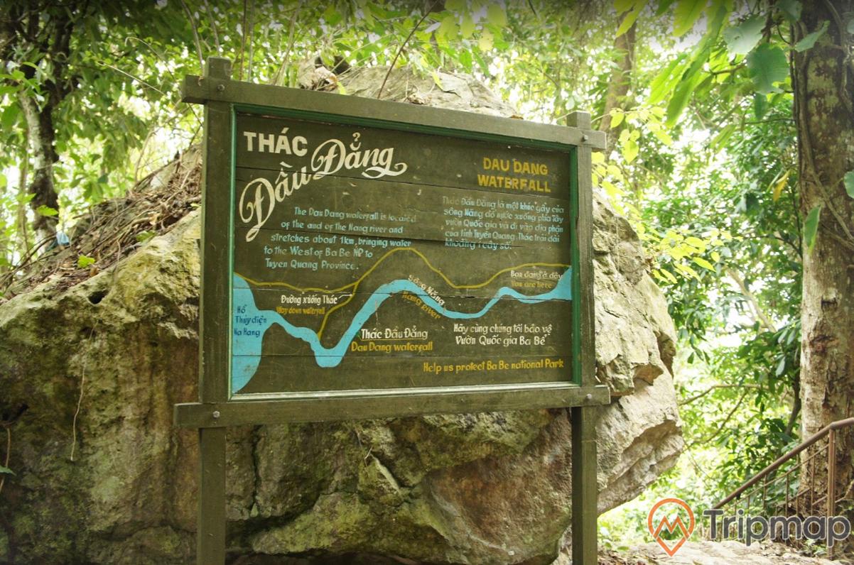 biển mô tả vị trí tại thác đầu đẳng, tấm bảng thông tin cạnh phiến đá lớn, cây cối