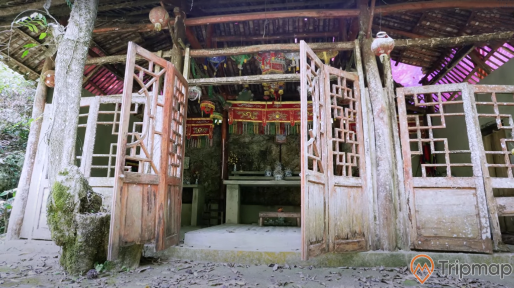 đền thời tại thác nà khoang, ảnh chụp bên ngoài ngôi đền, gốc cây phía trước ngôi đền, trong nhà có lồng đèn và bàn thờ
