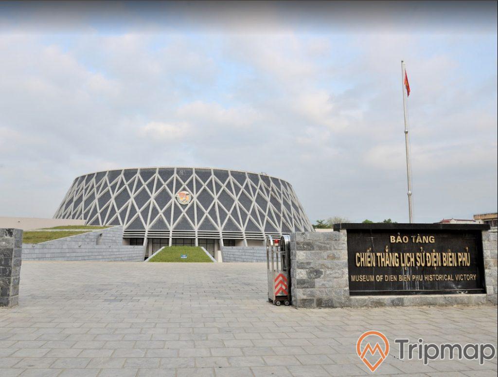 Bảo tàng chiến thắng lịch sử Điện Biên Phủ ( museum of dien bien phu historical victory ), lá cờ đỏ treo trên cột, bầu trời nhiều mây, ảnh chụp ngoài trời