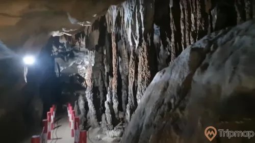 Cột nhũ đá trong hang động Xá Nhè, ánh đèn trắng trên vách đá, đường đi tham quan trong động, ảnh chụp trong hang động