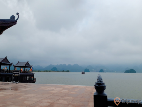 Bến đỗ du thuyền đón du khách tại khu du lịch hồ Tam Chúc, đồi núi phía xa xa, ảnh chụp ngoài trời, bầu trời nhiều mây đen