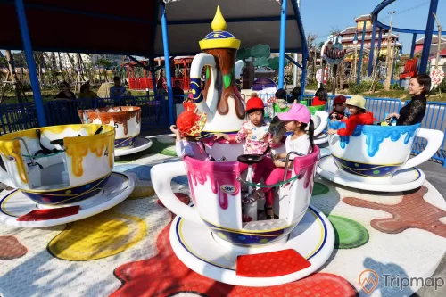 Choco-Cups, Chiếc Cốc Thần, nhiều mô hình cốc màu trắng, hàng rào sơn màu xanh, nhiều người đang ngồi trong mô hình cốc, trời nắng, ảnh chụp ban ngày