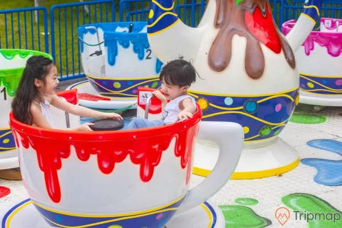 Choco-Cups, Chiếc Cốc Thần, nhiều mô hình cốc màu trắng, hàng rào sơn màu xanh, nhiều người đang ngồi trong mô hình cốc, trời nắng, ảnh chụp ban ngày