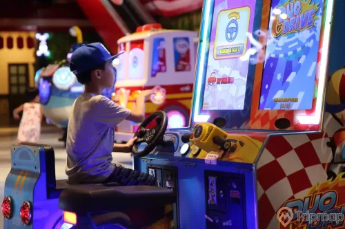 Khu video game xu xèng, cậu bé đang đội mũ xanh chơi trò chơi, máy điện tử xu xèng