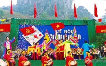 Lễ hội núi Voi, nhiều người mặc áo đỏ đánh trống, nhiều người đang nhảy múa, lá cờ việt nam, ngọn núi đá đằng sau, ảnh chụp ban ngày