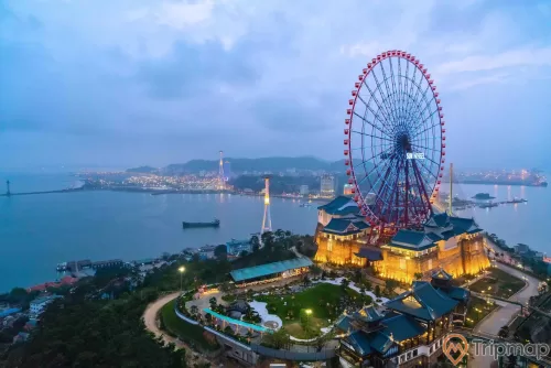 Sun Wheel , Vòng quay Mặt trời, khu vui chơi Khu đồi huyền bí ở phía dưới, nhiều cây xanh, khu dân cư ở phía xa, trời xanh, ảnh chụp từ trên cao, ảnh chụp buổi tối