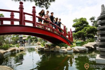 Vườn Nhật Bản Zen Garden, nhiều người đang đứng trên cây cầu màu đỏ, hồ nước bên dưới, nhiều cây xanh, ảnh chụp ban ngày