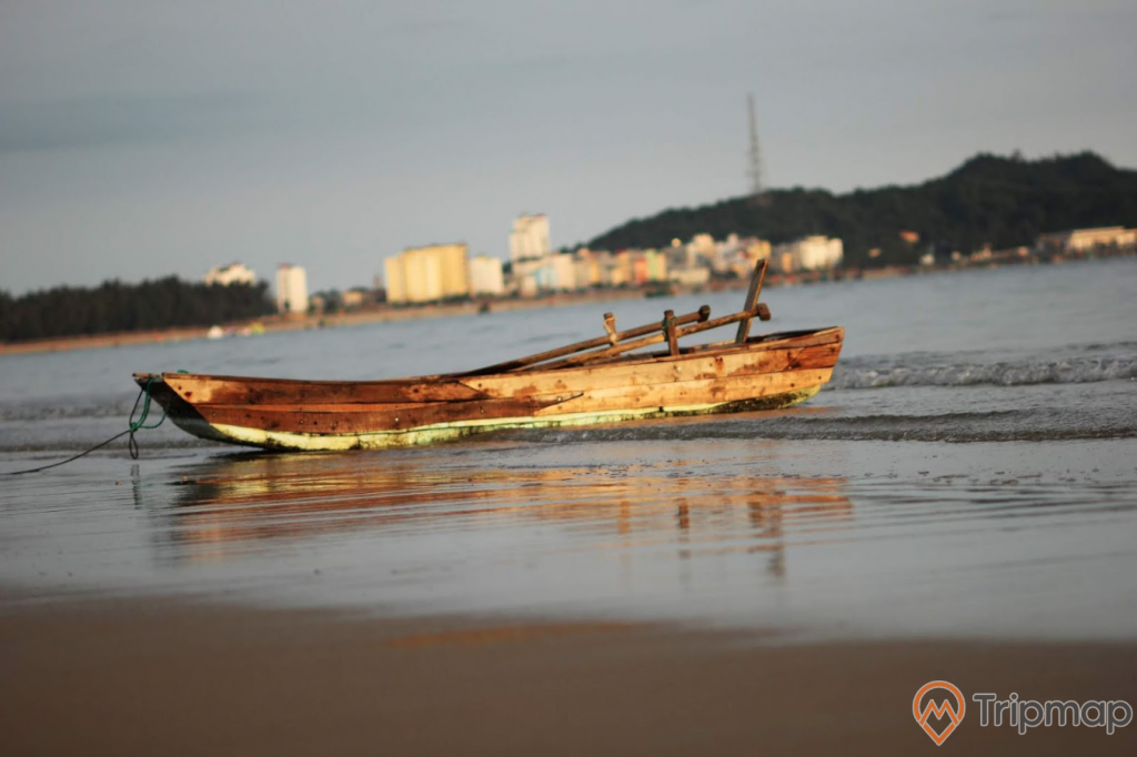 Chiếc thuyền gỗ trên bãi biển Tình Yêu, bầu trời nhiều mây, đảo phía xa xa