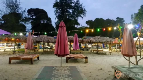 Khu nghỉ dưỡng ngay tại bãi biển Vàn Chảy, ảnh chụp vào lúc buổi chiều tối, cây cối xanh tươi gần bãi biển, những chiếc ô lá cọ và chiếc, ánh đèn sáng vào buổi tối,