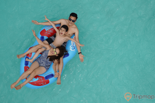 Bể bơi cho khách V.I.P, mặt nước bể bơi màu xanh, 3 người đang nằm trên chiếc phao màu xanh, ảnh chụp từ trên cao, ảnh chụp ban ngày
