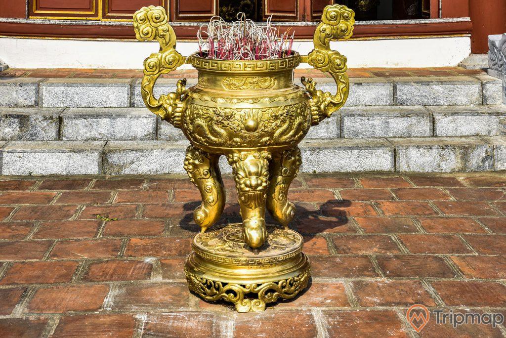 Chiếc lư hương bằng đồng ở đền thờ bác Hồ tại khu di tích lưu niệm Hồ Chủ tịch trên đảo Cô Tô, chiếc lư hương bằng đồng màu vàng đặt ngoài trời chính giữa sân đền thờ, bậc thềm đi vào đền thờ, ảnh chụp ngoài trời