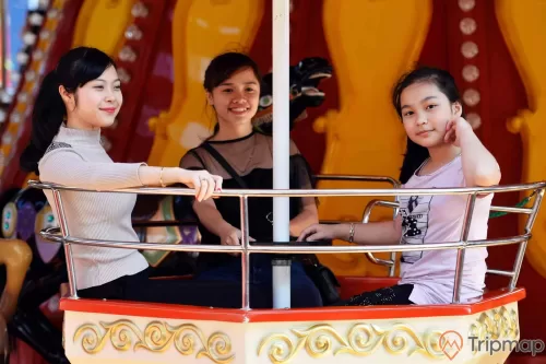 Royal Carousel, Đu Quay Kỳ Diệu, 3 người đang ngồi trên mô hình đu quay, ảnh chụp ban ngày