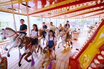 Royal Carousel, Đu Quay Kỳ Diệu, nhiều mô hình ngựa, nhiều người đang cưỡi mô hình ngựa, bên ngoài trời nắng, ảnh chụp ban ngày
