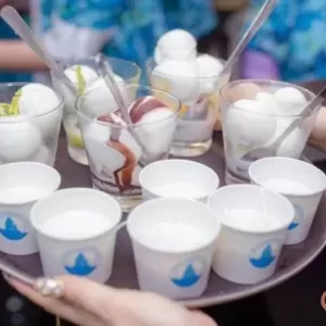 a table full of cups with straws and a hand holding a cup