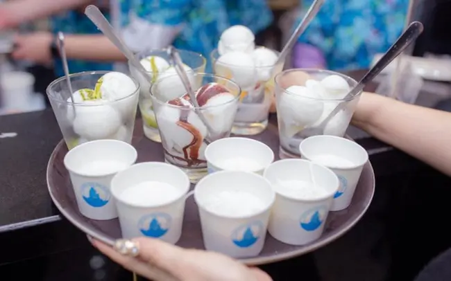 a table full of cups with straws and a hand holding a cup