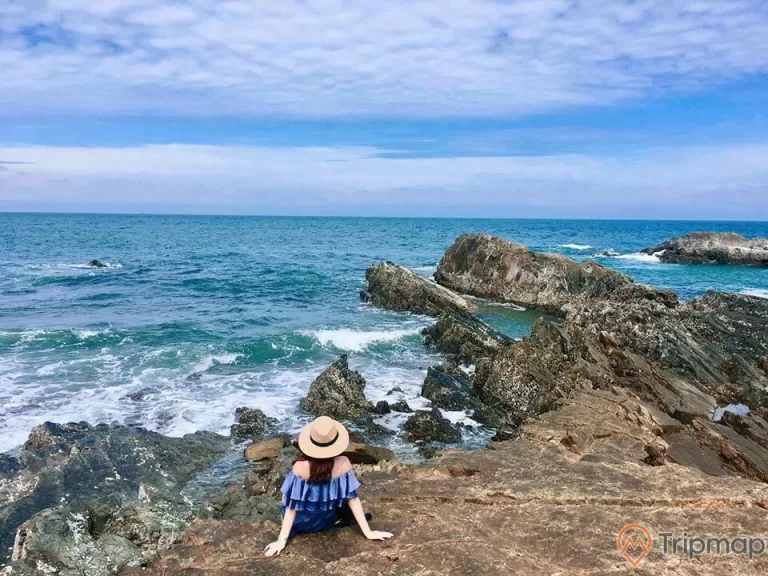 a child sitting on a rock by the ocean