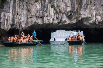 a group of people in boats in a cave with Ha Long Bay in the background