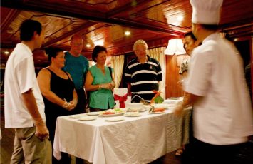 a group of people standing around a table with food on it