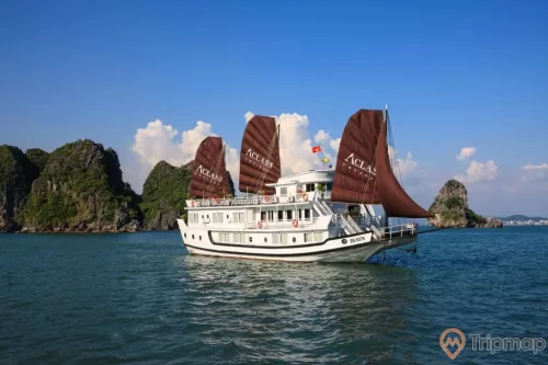 a boat with a large ship on it with Ha Long Bay in the background