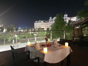 a table set with candles on a patio with a view of a city